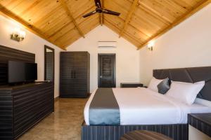 a bedroom with a bed and a flat screen tv at White Woods Resort, Morjim in Morjim