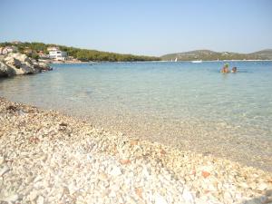 two people swimming in the water on a rocky beach at Apartmani Emily in Jezera