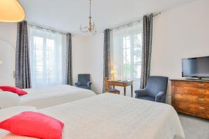 a bedroom with two beds and a flat screen tv at Hotel Royal Saint-Mart in Royat