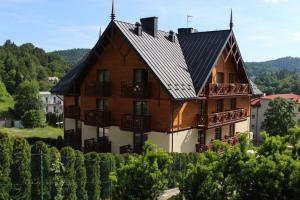 a large wooden house with a black roof at Pensjonat Gaborek in Krynica Zdrój