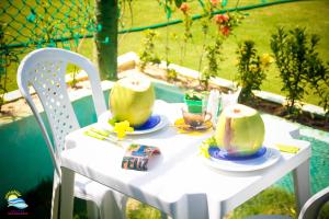 een witte tafel met twee kopjes en borden erop bij Villa Sirena Pousada de charme in Beberibe