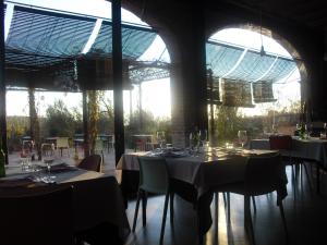 a dining room with tables and chairs and windows at Clos Figueras in Gratallops