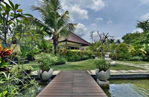 a garden with a wooden walkway in front of a house at Katala Suites and Villas in Sanur