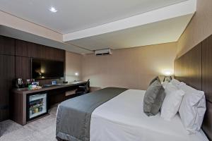 a hotel room with a bed and a tv at Slaviero Curitiba Centro in Curitiba