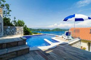einen Pool mit Sonnenschirm und Stuhl in der Unterkunft Adriatic-apartment & seaview pool in Sobra