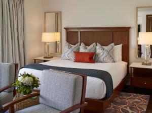 a bedroom with a bed with two chairs and two lamps at Inn By the Sea in Cape Elizabeth