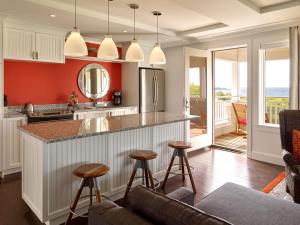 a kitchen with red walls and a counter with stools at Inn By the Sea in Cape Elizabeth