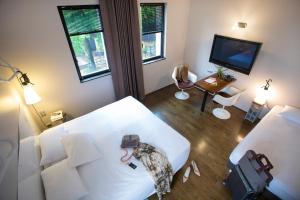 ein Schlafzimmer mit einem weißen Bett und einem Fernseher in der Unterkunft L'Ermitage Hôtel Cuisine-À-Manger in Saint-Cyr-au-Mont-dʼOr