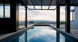 a swimming pool with a view of the ocean from a building at L'Ermitage Hôtel Cuisine-À-Manger in Saint-Cyr-au-Mont-dʼOr