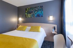 a hotel room with a bed with yellow pillows at Kyriad Niort-Espace MendesFrance in Niort