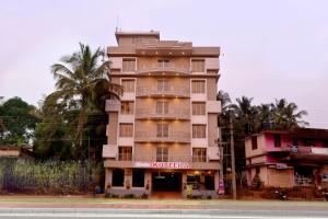 a tall tan building with a sign on it at Shesha KUTEERA in Subrahmanya