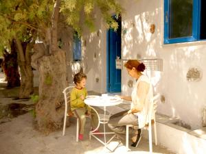 a woman and a child sitting at a table at Melenio Studios in Livadi Astypalaias