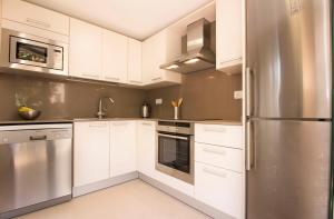 een keuken met witte kasten en een roestvrijstalen koelkast bij Apartamentos Elcano in Cambrils