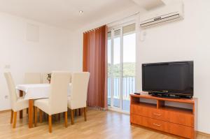 a living room with a tv and a table with chairs at Apartments Angelo in Polače +39 photos