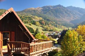 a wooden house with a balcony and mountains in the background at Gîte la Chamoussière in Saint-Mury-Monteymond