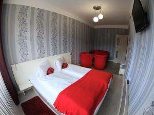 a bedroom with a white bed with a red blanket at Zajazd Tip Top in Iganie