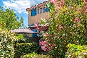 una casa con flores rosas y sombrilla en Résidence Goélia Sun Village, en Portiragnes