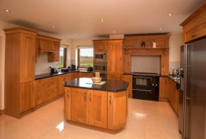 una cucina con armadi in legno e piano di lavoro nero di Cottage 238 – Cleggan a Cleggan