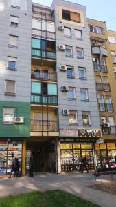 a tall apartment building with shops in front of it at Marina Jacuzzi Apartment free parking in Novi Sad