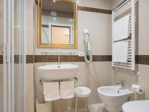 un bagno bianco con lavandino e specchio di Albergo Basilea a Venezia