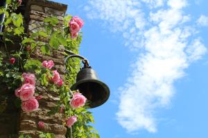 una campana su un muro di mattoni con rose rosa di Hewletts Mill a Castle Cary