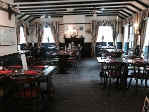 un comedor con mesas, sillas y ventanas en The Red Lion Inn & Restaurant en Prestatyn