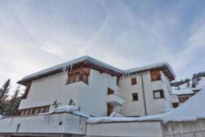 un bâtiment avec de la neige sur le toit dans l'établissement Chesa Sarvit - Celerina, à Celerina