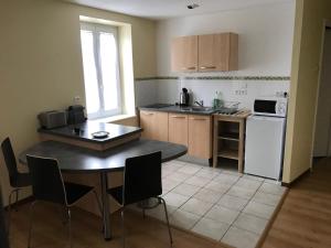 una pequeña cocina con mesa, mesa y sillas en Residence des portes du Velay en Saint-Didier-en-Velay