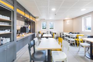 a dining room with tables and yellow chairs at B&B HOTEL Dijon Nord Zénith in Dijon