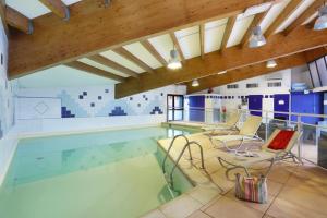 een groot zwembad met stoelen in een gebouw bij Suite Home Briancon Serre Chevalier in Briançon
