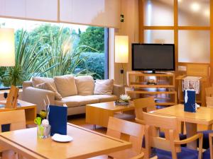 sala de estar con sofá, mesas y TV en Flag Hotel Valencia - Florazar, en Masalfasar