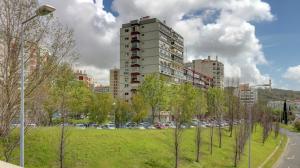 een park met bomen voor een hoog gebouw bij Casa de Benfica in Lissabon
