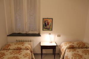 Terre Apartment في كورنيجليا: غرفة نوم بسريرين وطاولة بها مصباح