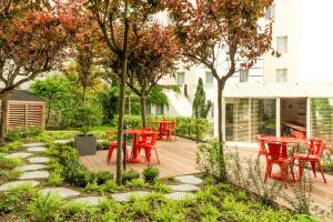 une terrasse en bois avec des chaises et des tables rouges dans un jardin dans l'établissement ibis Paris Gare du Nord La Fayette, à Paris