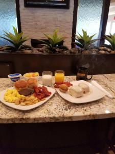 two plates of breakfast food on a counter with drinks at Club Hotel Nashville Inn & Suites in Nashville
