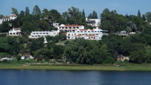 a group of white houses on a hill next to a lake at Hotel Marqués del Lago in Villa Carlos Paz