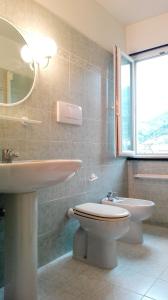 Un baño con lavabo, inodoro y espejo. en Monia House Sea View, en Levanto