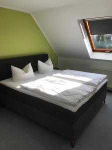 1 cama con sábanas blancas y almohadas en una habitación en Hotel am Maibaum, en Neuenrade