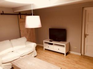 a living room with a white couch and a flat screen tv at Ferienwohnung Feldblick in Grevenkop