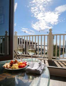 una mesa con una bandeja de fruta y copas de vino en el balcón en Almondy Inn Bed & Breakfast, en Newport