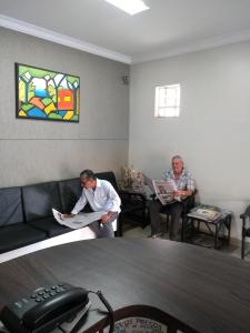 two men sitting in a waiting room reading newspapers at Hotel Triunfo in Londrina
