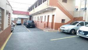 a parking lot with cars parked in front of a building at Hotel Triunfo in Londrina