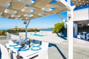 a patio with a table and chairs under a pergola at Evangelos Villas, lavish touch, By ThinkVilla in Angeliana