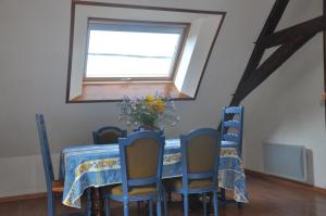 un tavolo da pranzo con sedie blu e una finestra di Gîte la Chamoussière a Saint-Mury-Monteymond