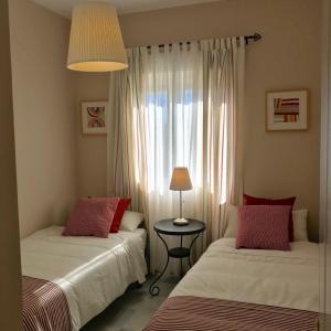ロタにあるApartamento Costa Ballenaのベッドルーム1室(ベッド2台、ランプ付きテーブル付)