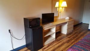 a hotel room with a desk with a tv and a computer at Red Carpet Inn in Gibbstown