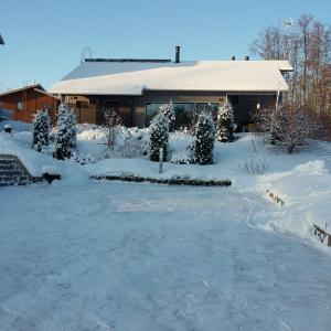 a house covered in snow with trees in the yard at Villa Graniitti in Imatra