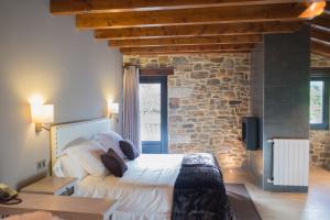 Un dormitorio con una cama y una pared de piedra. en Osabarena Hotela, en Murueta-Orozko