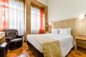 a hotel room with a bed, chair, and nightstand at Santa Clara Porto in Porto