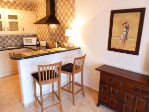 a kitchen with a bar with two chairs and a table at 1 Bed Traditional Holiday Rental Cottage Oasis Capistrano Nerja Spain in Nerja